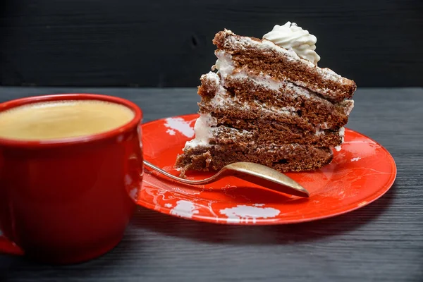 Kremalı ekşi pasta ve kırmızı bardakta taze kahve.