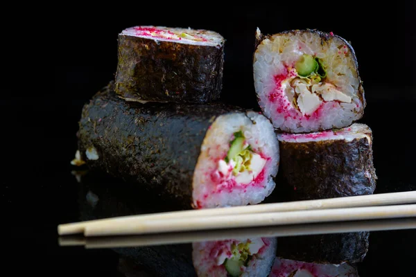 Suşi siyah ayna arka planında yuvarlanıyor..