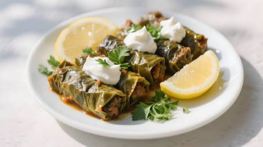 Dolma ya da tolma, ekşi krema, limon, beyaz tabakta maydanoz. Üst görünüm, boşluğu kopyala. Geleneksel Kafkas, Türk, Ermeni ve Yunan mutfağı