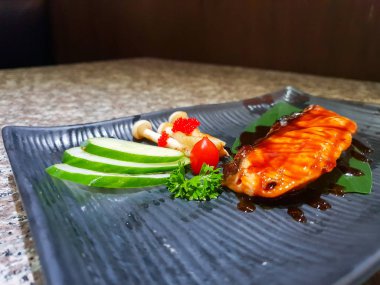 Ahşap masa üzerinde siyah taş tabakta servis sebzeli ızgara somon