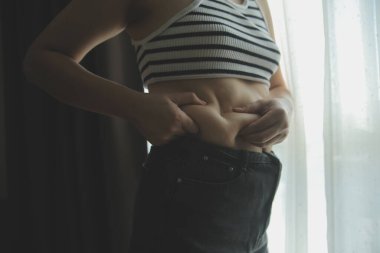 Kadın göbeği. Şişman kadın göbek yağlarını tutuyor. diyet yaşam tarzı konsepti karın kaslarını zayıflatmak ve sağlıklı mide kaslarını şekillendirmek için.