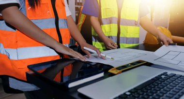 Endüstriyel mühendislerden oluşan bir ekip, fabrikadaki masada bulunan makine planlarını analiz ediyor. Fabrikada ya da üretim tesisinde çalışıyorum..