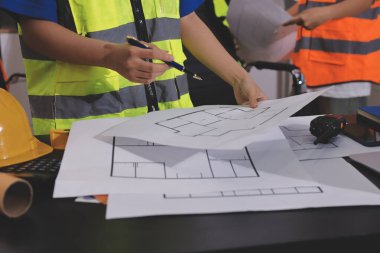 Endüstriyel mühendislerden oluşan bir ekip, fabrikadaki masada bulunan makine planlarını analiz ediyor. Fabrikada ya da üretim tesisinde çalışıyorum..