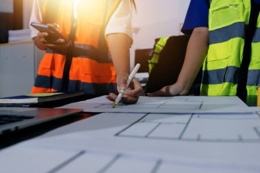 Endüstriyel mühendislerden oluşan bir ekip, fabrikadaki masada bulunan makine planlarını analiz ediyor. Fabrikada ya da üretim tesisinde çalışıyorum..