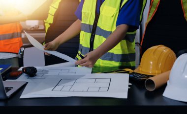 Endüstriyel mühendislerden oluşan bir ekip, fabrikadaki masada bulunan makine planlarını analiz ediyor. Fabrikada ya da üretim tesisinde çalışıyorum..