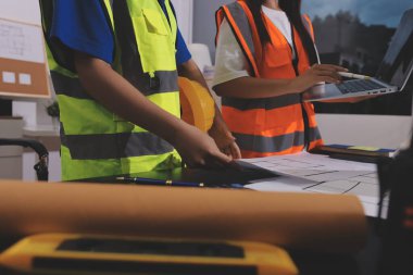 Endüstriyel mühendislerden oluşan bir ekip, fabrikadaki masada bulunan makine planlarını analiz ediyor. Fabrikada ya da üretim tesisinde çalışıyorum..