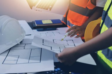 Endüstriyel mühendislerden oluşan bir ekip, fabrikadaki masada bulunan makine planlarını analiz ediyor. Fabrikada ya da üretim tesisinde çalışıyorum..