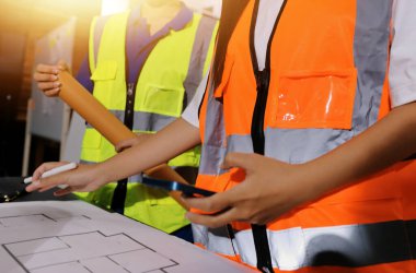 Endüstriyel mühendislerden oluşan bir ekip, fabrikadaki masada bulunan makine planlarını analiz ediyor. Fabrikada ya da üretim tesisinde çalışıyorum..