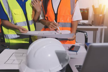 Endüstriyel mühendislerden oluşan bir ekip, fabrikadaki masada bulunan makine planlarını analiz ediyor. Fabrikada ya da üretim tesisinde çalışıyorum..