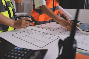 Endüstriyel mühendislerden oluşan bir ekip, fabrikadaki masada bulunan makine planlarını analiz ediyor. Fabrikada ya da üretim tesisinde çalışıyorum..