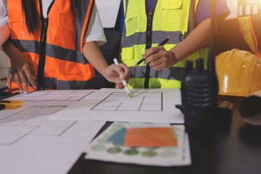 Endüstriyel mühendislerden oluşan bir ekip, fabrikadaki masada bulunan makine planlarını analiz ediyor. Fabrikada ya da üretim tesisinde çalışıyorum..