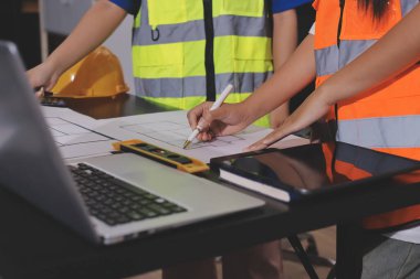Endüstriyel mühendislerden oluşan bir ekip, fabrikadaki masada bulunan makine planlarını analiz ediyor. Fabrikada ya da üretim tesisinde çalışıyorum..