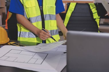 Endüstriyel mühendislerden oluşan bir ekip, fabrikadaki masada bulunan makine planlarını analiz ediyor. Fabrikada ya da üretim tesisinde çalışıyorum..