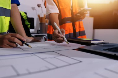 Endüstriyel mühendislerden oluşan bir ekip, fabrikadaki masada bulunan makine planlarını analiz ediyor. Fabrikada ya da üretim tesisinde çalışıyorum..