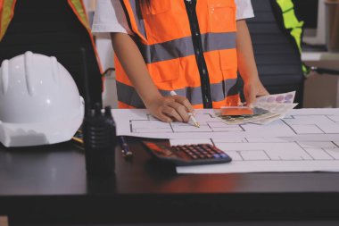 Endüstriyel mühendislerden oluşan bir ekip, fabrikadaki masada bulunan makine planlarını analiz ediyor. Fabrikada ya da üretim tesisinde çalışıyorum..