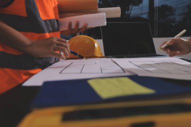 Endüstriyel mühendislerden oluşan bir ekip, fabrikadaki masada bulunan makine planlarını analiz ediyor. Fabrikada ya da üretim tesisinde çalışıyorum..