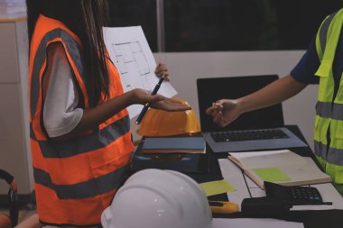 Endüstriyel mühendislerden oluşan bir ekip, fabrikadaki masada bulunan makine planlarını analiz ediyor. Fabrikada ya da üretim tesisinde çalışıyorum..