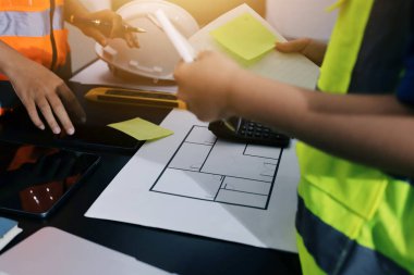 Endüstriyel mühendislerden oluşan bir ekip, fabrikadaki masada bulunan makine planlarını analiz ediyor. Fabrikada ya da üretim tesisinde çalışıyorum..