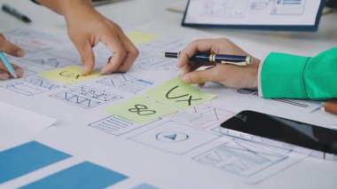 Modern çalışma ortamında akıllı telefon kullanan ve deftere yazı yazan genç iş kadınlarını kapatın..