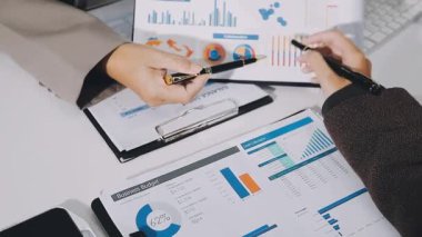 İşadamı ofis masasına kalemle mali rapor yazıyor.