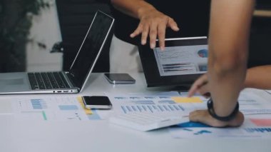 Genç iş kadını tablet bilgisayar kullanıyor ve ofis masasındaki çizelgelere işaret ediyor. iş, teknoloji, finans kavramı.