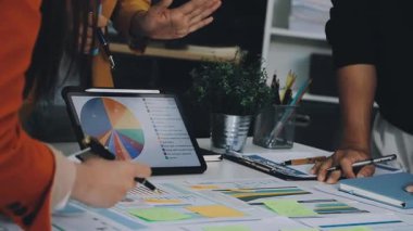 Takım elbiseli ve gömlekli genç bir kadın ofiste oturuyor ve dizüstü bilgisayarla çalışıyor.