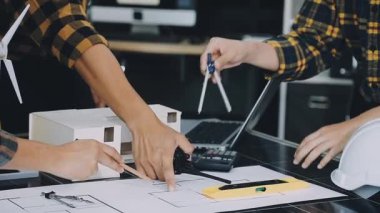 Genç Asyalı mimar evde planla çalışıyor.