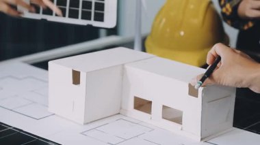 Yeni bir ev modeli üzerinde çalışan erkek mimara yakın plan ve planlar ofisteki bir masada.
