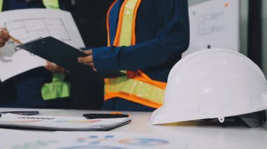 Taslak ve tabletle inşaat sahasında çalışan Asyalı mühendis.