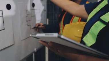 Miğferli genç bayan mimar, ofis inşaatında tablet bilgisayar ve planla çalışıyor..