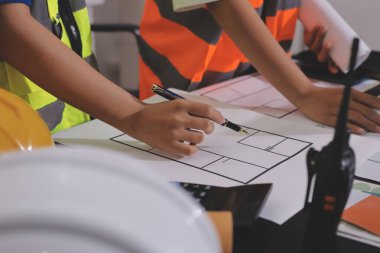 Endüstriyel mühendislerden oluşan bir ekip, fabrikadaki masada bulunan makine planlarını analiz ediyor. Fabrikada ya da üretim tesisinde çalışıyorum..