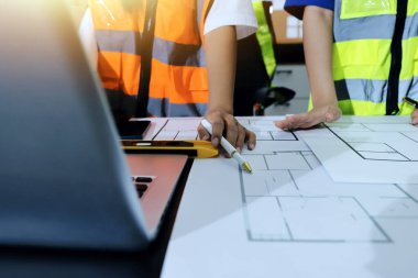 Endüstriyel mühendislerden oluşan bir ekip, fabrikadaki masada bulunan makine planlarını analiz ediyor. Fabrikada ya da üretim tesisinde çalışıyorum..