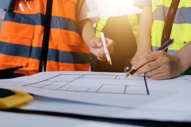 Endüstriyel mühendislerden oluşan bir ekip, fabrikadaki masada bulunan makine planlarını analiz ediyor. Fabrikada ya da üretim tesisinde çalışıyorum..