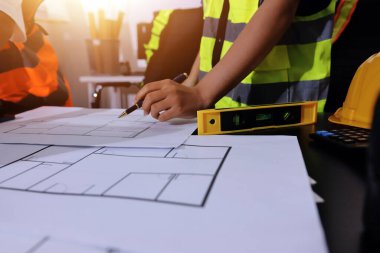 Endüstriyel mühendislerden oluşan bir ekip, fabrikadaki masada bulunan makine planlarını analiz ediyor. Fabrikada ya da üretim tesisinde çalışıyorum..