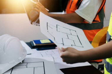 Endüstriyel mühendislerden oluşan bir ekip, fabrikadaki masada bulunan makine planlarını analiz ediyor. Fabrikada ya da üretim tesisinde çalışıyorum..