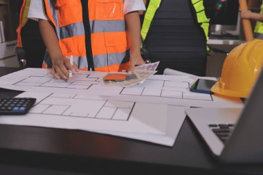 Endüstriyel mühendislerden oluşan bir ekip, fabrikadaki masada bulunan makine planlarını analiz ediyor. Fabrikada ya da üretim tesisinde çalışıyorum..