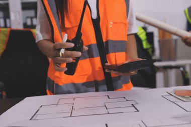 Endüstriyel mühendislerden oluşan bir ekip, fabrikadaki masada bulunan makine planlarını analiz ediyor. Fabrikada ya da üretim tesisinde çalışıyorum..