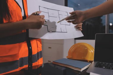 Endüstriyel mühendislerden oluşan bir ekip, fabrikadaki masada bulunan makine planlarını analiz ediyor. Fabrikada ya da üretim tesisinde çalışıyorum..