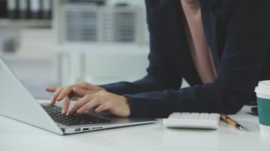 Ofisteki belgelerle uğraşırken elinde laptop ve akıllı telefon tutan bir işadamı.