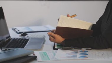 İş kadını kalem tutuyor ve dizüstü bilgisayar kullanıyor.