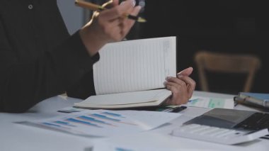 Bir kafede doküman ve bilgisayarla çalışan genç bir iş kadını.