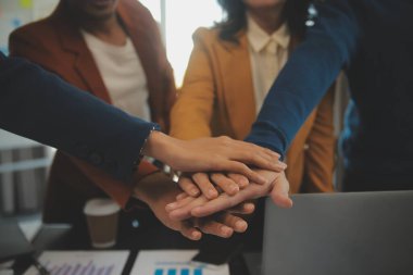 Genç Asyalı girişimciler ve girişimciler iş toplantısı yapıyorlar ve başarılı pazarlama planı konseptini gerçekleştirmek için ruhsal enerji için birbirlerini teşvik ediyorlar.