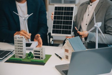 İki Genç Mühendis Güneş Hücresi Kurulum Toplantısı ve İş Tartışması Uzmanı. Ofis Odası 'nda Fabrika İnşaat Planlı Çatı Üzerine Güneş Fotovoltaik Panelleri Kurmayı Planlıyorum.