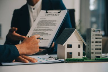 Emlakçı ev satın alma anlaşmasının şartları hakkında konuştu ve müşteriden sözleşmeyi yasal hale getirmek için belgeleri imzalamasını istedi, ev satışları ve ev sigortası kavramı.