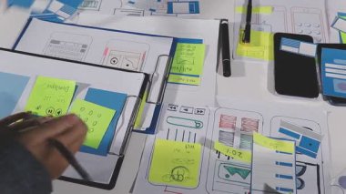 Masasında yapışkan bir notla cep telefonu ve tablet üzerinde çalışan yaratıcı tasarımcı