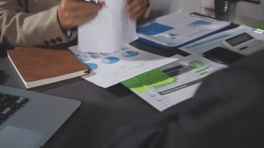 Genç işadamı görevdeki dizüstü bilgisayarında grafik ve grafiklerle verileri analiz ediyor.