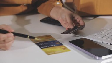 Kadın kredi kartıyla ödeme yapıyor ve evde dizüstü bilgisayar kullanıyor.