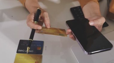 Adam kredi kartı tutuyor ve alışveriş için cep telefonu kullanıyor.