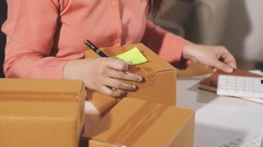 Kadın elinde karton kutu ve kalemle evde bekliyor.