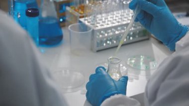 Bilim adamı deney tüpünü pipetle tutuyor.